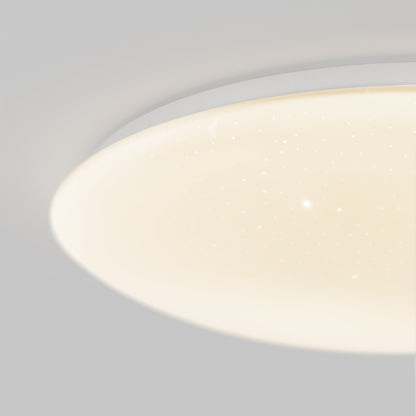 A close-up of the Artika Empress 13 in. LED modern flush mount light, ceiling-mounted with a white finish, glows warmly with star-like sparkles on its surface against a neutral background. Features selectable 3 CCT color temperatures.