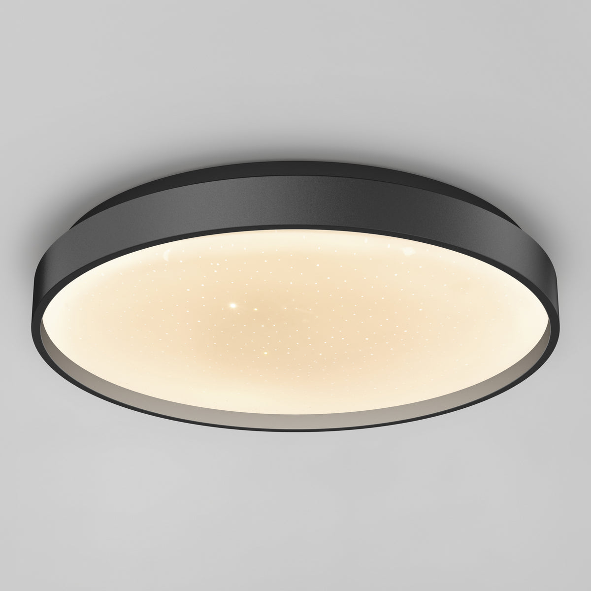 A modern, round ceiling light with a black frame and a glowing white diffuser, featuring tiny speckles that resemble stars against a smooth, light gray ceiling.
