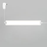 A rectangular white LED light fixture is mounted on a light gray wall, connected to a white power adapter with a cable. The light is turned on, emitting a bright glow.