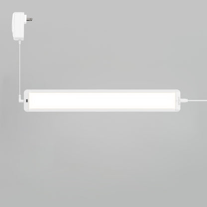 The Artika Maestro under cabinet LED light 3CCT is installed on a light grey wall, with a white power adapter connected by a cable on the left.