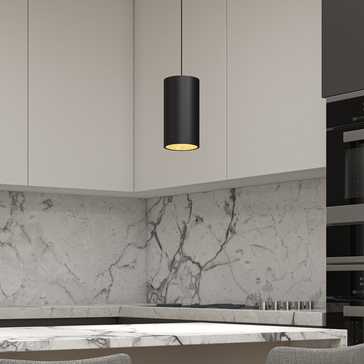 Modern kitchen with light gray marble backsplash and countertop, white upper cabinets, a black cylindrical pendant light hanging from the ceiling, and part of a built-in oven visible on the right.