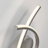A modern wall light fixture with two curved, intersecting LED bars mounted on a rounded, brushed metal base against a light gray wall. The fixture emits a soft, warm glow.