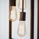 Close-up of three illuminated vintage-style Edison light bulbs with exposed filaments, hanging from metallic sockets against a softly blurred background.