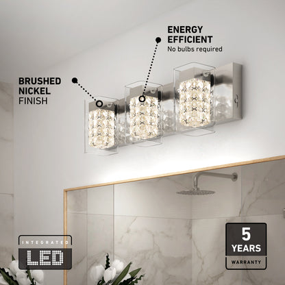 Artika’s Crystal Cube LED bathroom vanity light 5 CCT features three crystal-inspired lights in a brushed nickel finish above a mirror. Integrated LED delivers energy efficiency and comes with a 5-year warranty. White flowers are also in view.