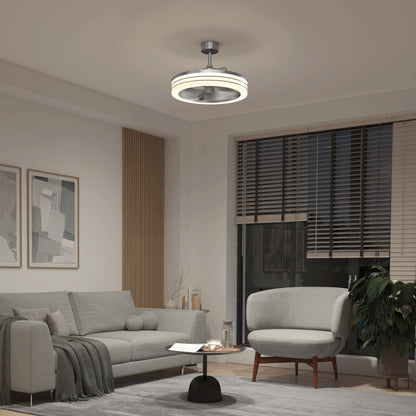 A modern living room features a gray sofa, round armchair, small black coffee table, wall art, potted plant, and the Artika Horizon 23 in. LED modern ceiling fan with remote. Large windows with blinds fill the space with natural light.