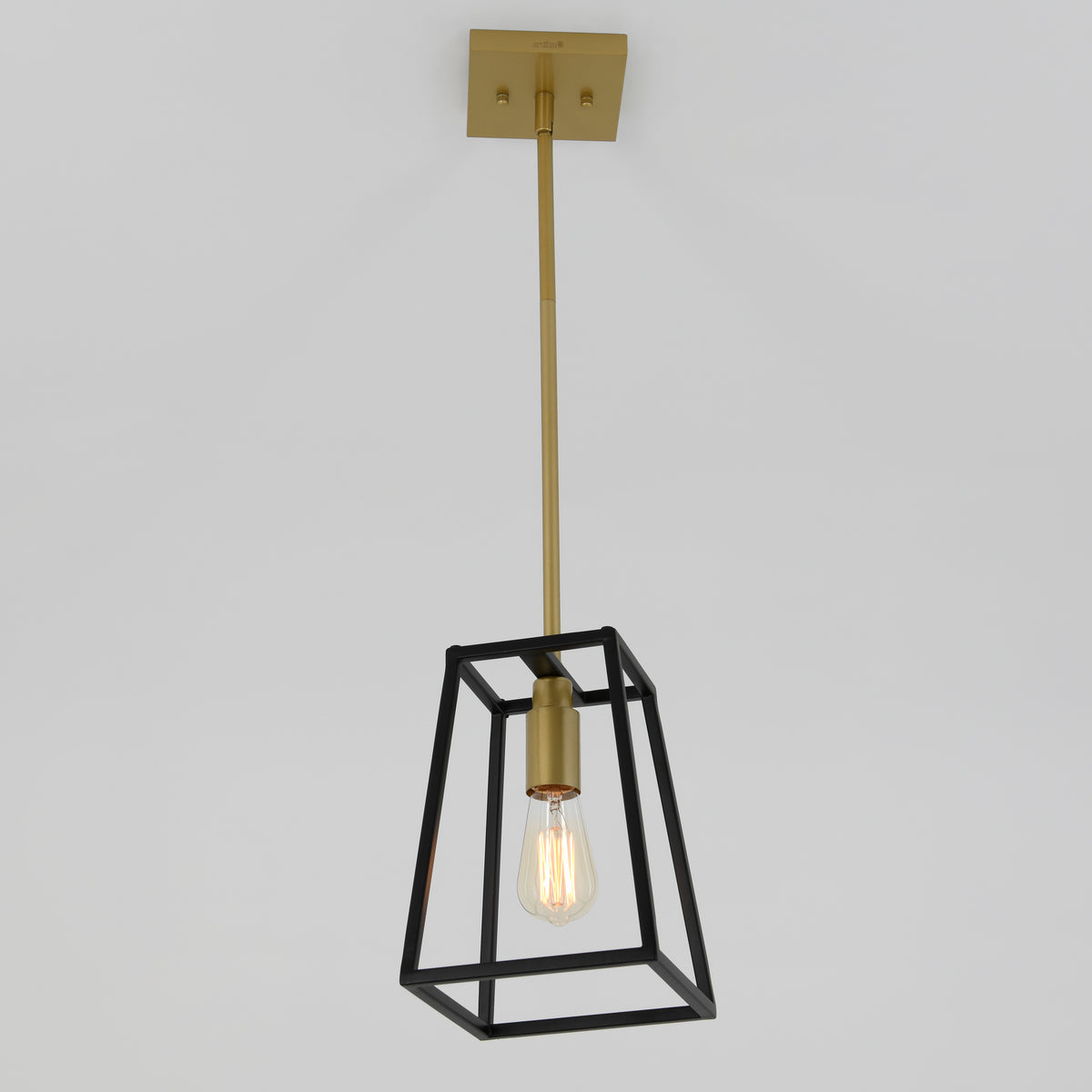A modern pendant light with a brass rod and fixture, featuring an exposed bulb inside a black geometric metal frame, hanging from a white ceiling.