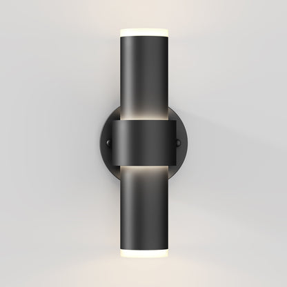 The Artika Dani modern LED indoor-outdoor wall light 5 CCT features a sleek cylindrical black design on a round base, emitting light from both the top and bottom against a light gray wall.