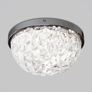 The Artika Carat LED flush mount light features a dome-shaped, faceted glass cover and a shiny metallic base, casting a bright, sparkling glow against a plain gray background.