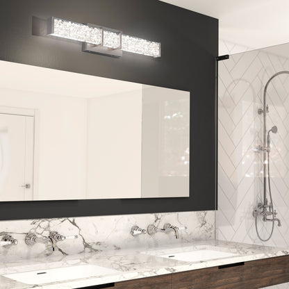 Modern bathroom with a double sink vanity, marble countertop, large mirror, wall-mounted faucets, and a glass-enclosed shower with herringbone tile. Above the mirror is the Artika Royale LED bathroom vanity light.