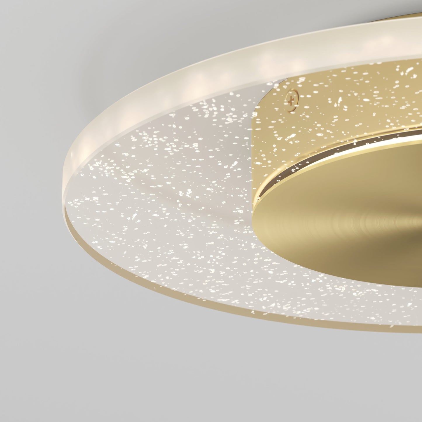 Close-up of the Essence Disk LED flush mount by Artika-CAN-dev, featuring a gold circular base and transparent haloed glass diffuser with white speckles for a starry effect, mounted on a plain light gray ceiling.