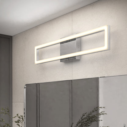 The Artika Dover modern LED bathroom vanity light 5 CCT, featuring a sleek metallic base, is installed above a bathroom mirror on a light-tiled wall. Partially visible plants accent the scene in the lower left corner.