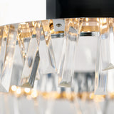 Close-up of a modern chandelier featuring clear, rectangular crystal prisms hanging from a circular metallic frame, with warm light reflecting through the crystals.