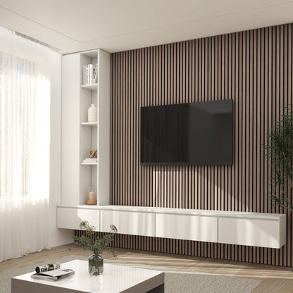 Modern living room featuring Artikas Sonolok sound-absorbing wall panel kit behind a wall-mounted TV, white floating shelves and cabinets, a coffee table with books and a vase, large window with sheer curtains, and a green plant in the corner.