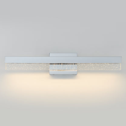 The Artika Essence Bubble Bar LED bathroom vanity light features a rectangular metal base and a frosted glass bar with air bubbles, casting a soft, warm glow against neutral walls.