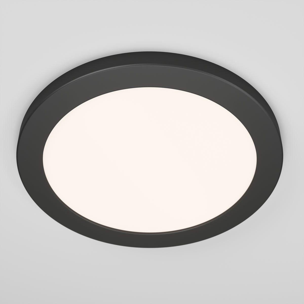 A round, modern ceiling light with a black frame and a white illuminated center, mounted on a white ceiling.
