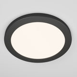 A round, modern ceiling light with a black frame and a white illuminated center, mounted on a white ceiling.
