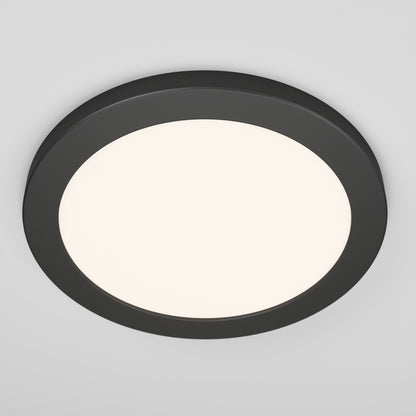 A round, modern ceiling light with a black frame and a white illuminated center, mounted on a white ceiling.