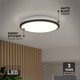 A round ceiling light with a matte black finish is illuminated in a modern room. Text highlights its energy efficiency, integrated LED feature, and a 3-year warranty. A wooden accent wall is visible below the light.