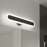 A modern, oval-shaped wall light fixture with a glowing white border mounted above a mirror in a minimalist bathroom with white and dark gray walls.