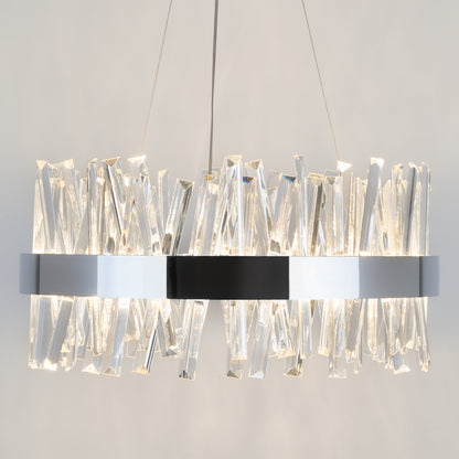 The Enchanted LED pendant light by Artika features a circular chrome frame with angled crystal prisms, suspended by two thin wires, casting a bright warm glow against a neutral background.