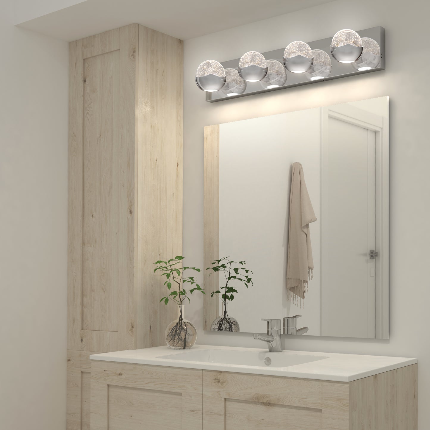 Modern bathroom with light wood cabinets, white countertop and sink, large mirror, two small potted plants, towel on the wall, and an Artika Oracle LED bathroom vanity light mounted above the mirror.