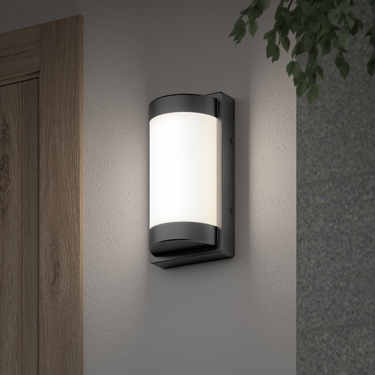 A modern black and white outdoor wall sconce is mounted beside a wooden door on a light-colored wall, with green leaves visible in the upper right corner.