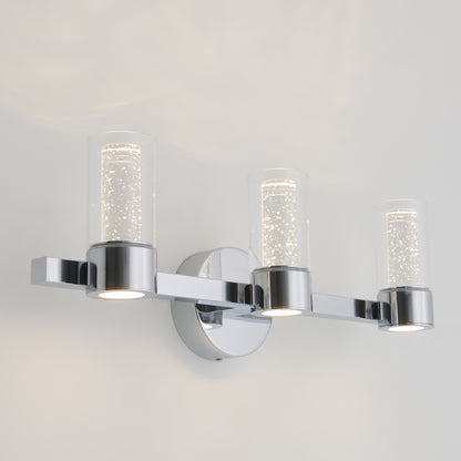 The Artika Novello modern LED bathroom vanity light features three bubble-glass cylindrical shades and a sleek chrome base, mounted against a plain white wall.