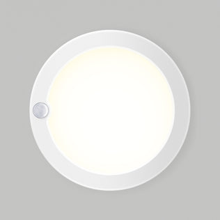 The Artika Accent under cabinet LED light 3CCT is a round, white fixture with a glowing center and a small sensor on the edge, designed for mounting on flat surfaces.
