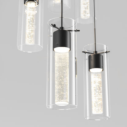 Close-up of the Artika Essence 5-light LED pendant, featuring cylindrical glass shades and black metal fixtures with glowing textured inner tubes, casting a soft light against a neutral backdrop.