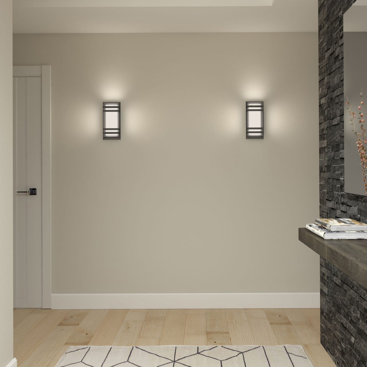 A modern, minimalist room with pale wood flooring, a geometric-patterned rug, two wall sconces emitting soft light, a white door, and a stone accent wall with a floating shelf holding decorative items.