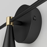 Close-up of a modern black wall-mounted light fixture with a round base and a gold accent where the rod meets the base, set against a plain light background.