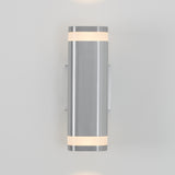 A modern wall sconce with a cylindrical brushed metal body and frosted glass bands at the top and bottom, emitting soft light upward and downward, mounted on a light gray wall.