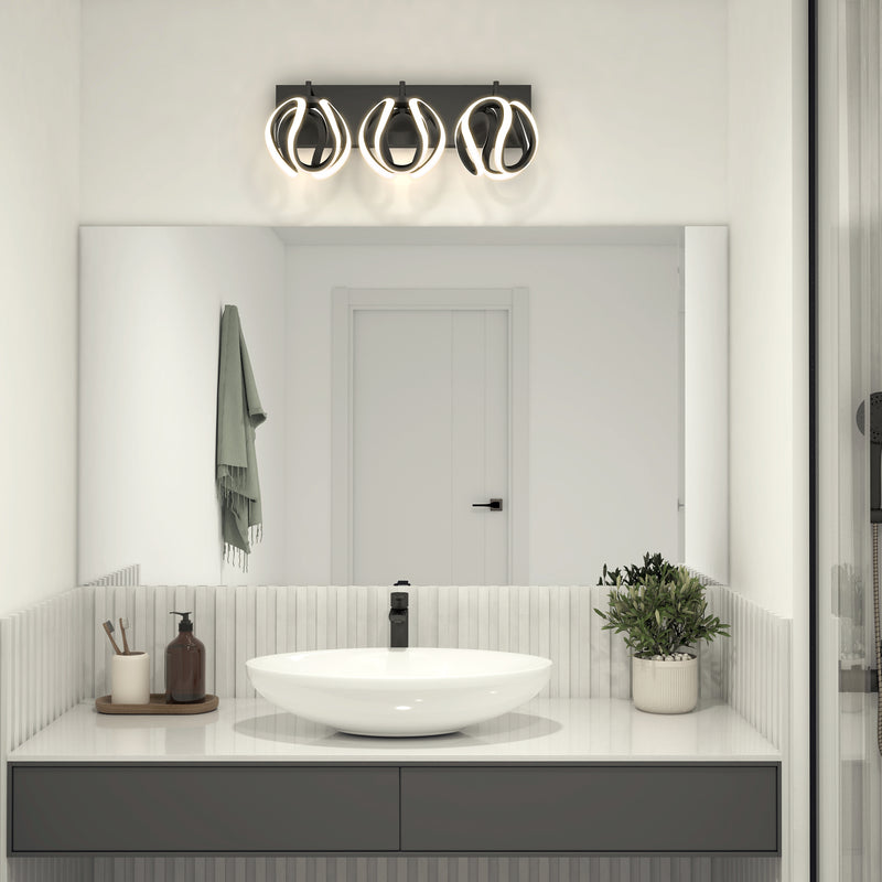 Modern bathroom with a round white sink, black faucet, potted plant, bottles, and towel on the counter. A large mirror reflects a closed white door and the Artika Vivaldi LED contemporary bathroom vanity light above, enhancing the décor.