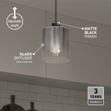A modern pendant light with a clear glass diffuser and matte black finish hangs from the ceiling. Text highlights its adjustable height and 3-year warranty. White subway tiles and cabinets are visible in the background.