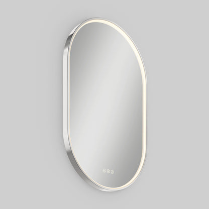 The Artika Royce LED mirror 3 CCT with defogger is a modern, oval wall mirror featuring edge LED lighting and three touch-sensitive buttons at the bottom, mounted on a light gray wall.