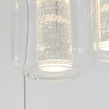 Close-up of the Artika Champagne Globe 4-light LED pendant, showcasing its modern clear glass shade and illuminated cylindrical diffuser with sparkling bubble details.