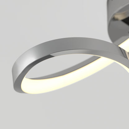 Close-up of a modern, curved LED wall light with a metallic silver finish and a glowing white strip along the inner edge, mounted against a plain light gray background.