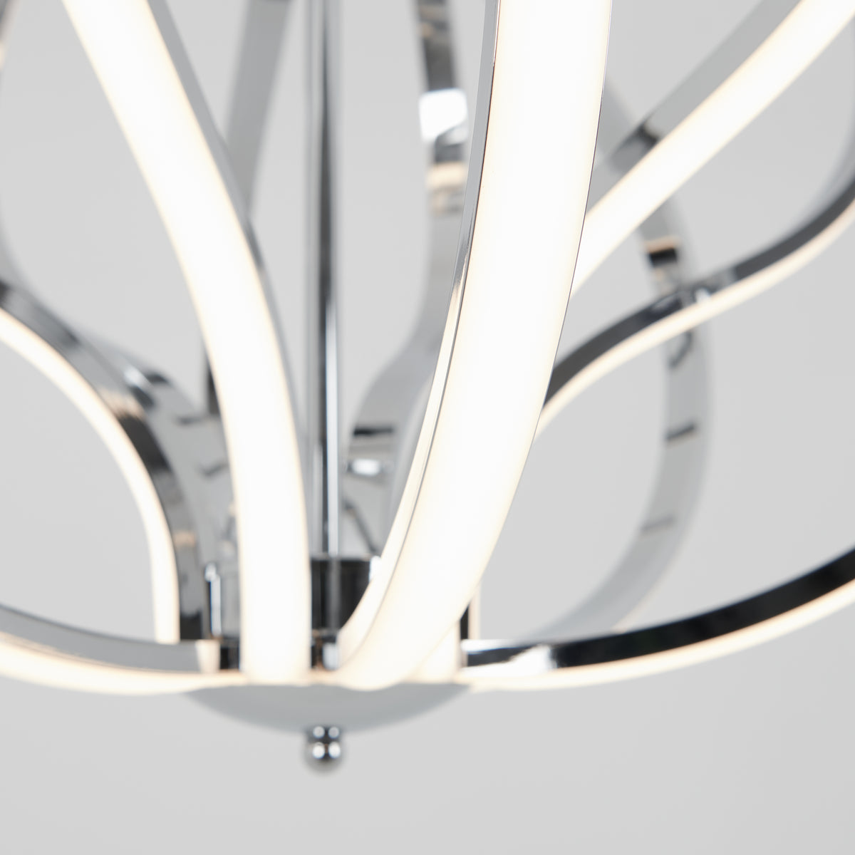 Close-up of a modern chandelier with curved, chrome arms and integrated LED light strips, set against a plain, light gray background.