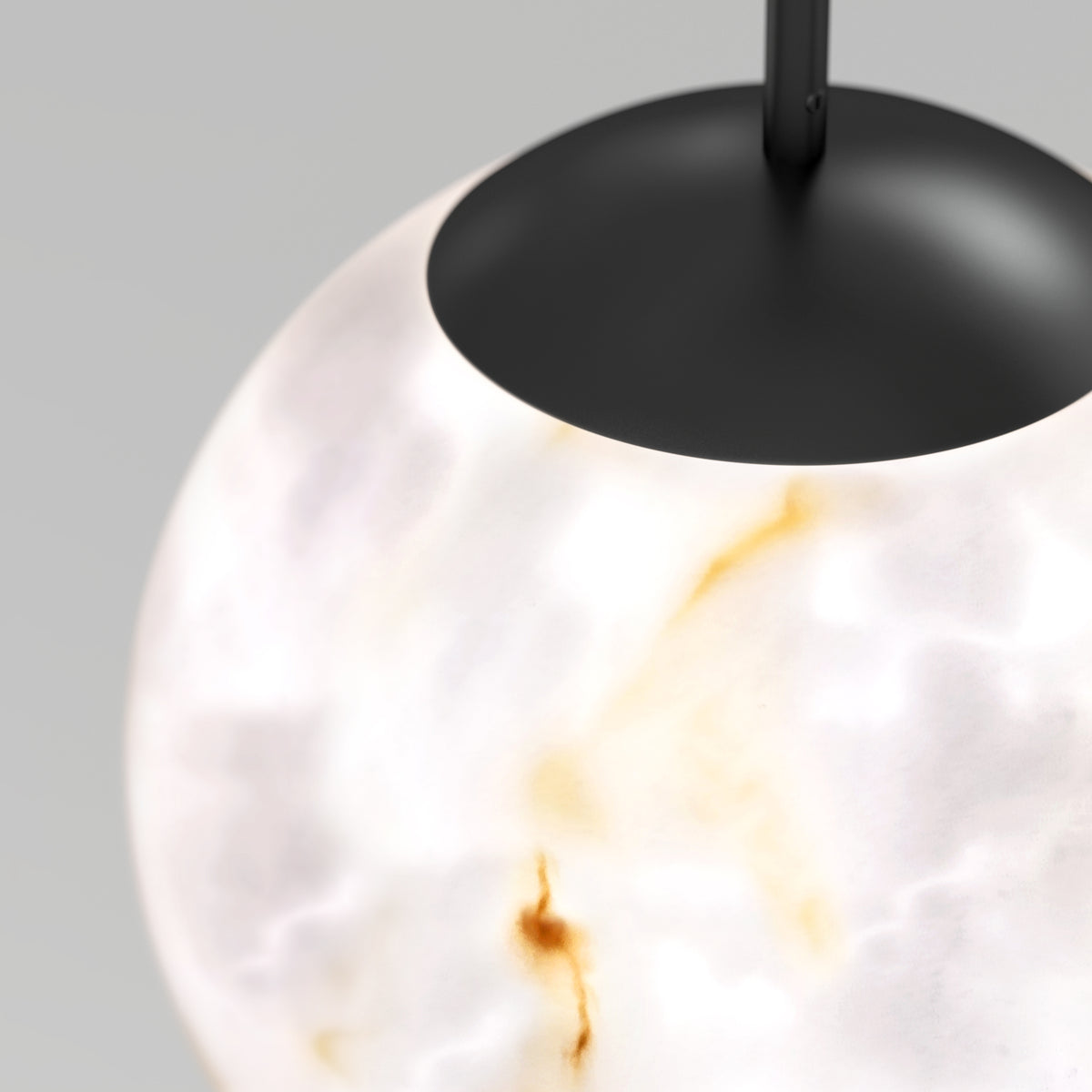 Close-up of a modern hanging light fixture with a round, frosted white shade featuring subtle brownish-gold marble-like patterns and a matte black top.