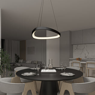 A modern dining area with a round black table for four sits beneath the Artika Bjorn modern LED pendant light 5 CCT. The space has minimalist decor, light wood chairs, and an open kitchen in the background.