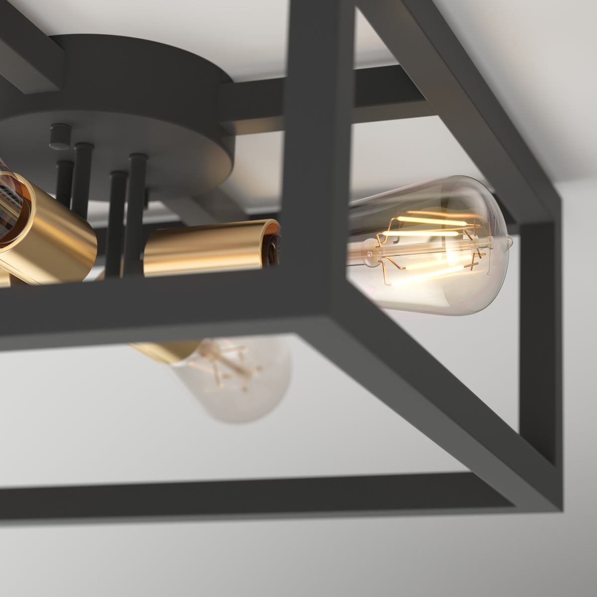 A close-up of a modern ceiling light fixture with exposed bulbs, gold sockets, and a black metal rectangular frame mounted on a white ceiling.