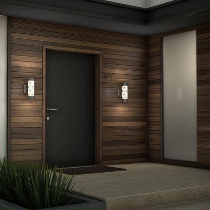 A modern entryway features a dark wooden door, horizontal siding, frosted glass panel, a doormat, a small green planter, and two Artika Bubble Element LED indoor-outdoor lights mounted on either side of the door.