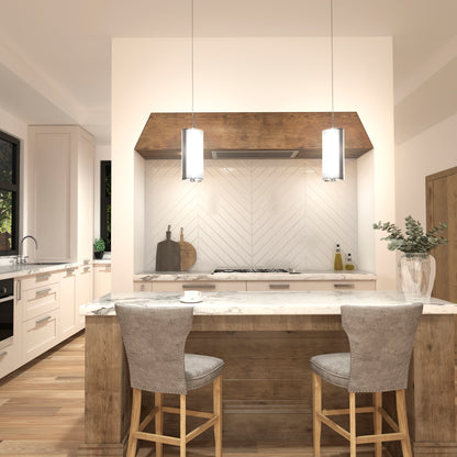 Modern kitchen featuring a marble island, two upholstered stools, wood accents, and a chevron backsplash. Artika Subway Round Mini LED pendant lights illuminate the space. A vase with greenery sits on the counter in this light, neutral setting.