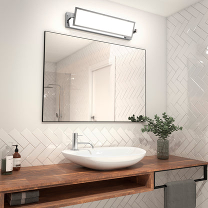 A modern bathroom featuring white herringbone tiles, a wooden countertop with vessel sink, wall-mounted rectangular mirror, Artika’s Reflection Flat Panel LED vanity light above, and a small green plant beside soap and a towel.