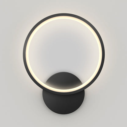 The Artika Solis modern LED indoor-outdoor wall light 5 CCT features a circular LED ring on a round black base, delivering a soft, even glow against a light gray wall.
