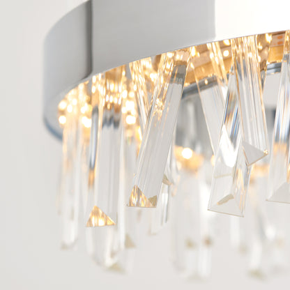 Close-up of the Artika Enchanted LED pendant light, showcasing clear, angular crystal prisms on a silver circular frame, beautifully lit by warm LEDs.