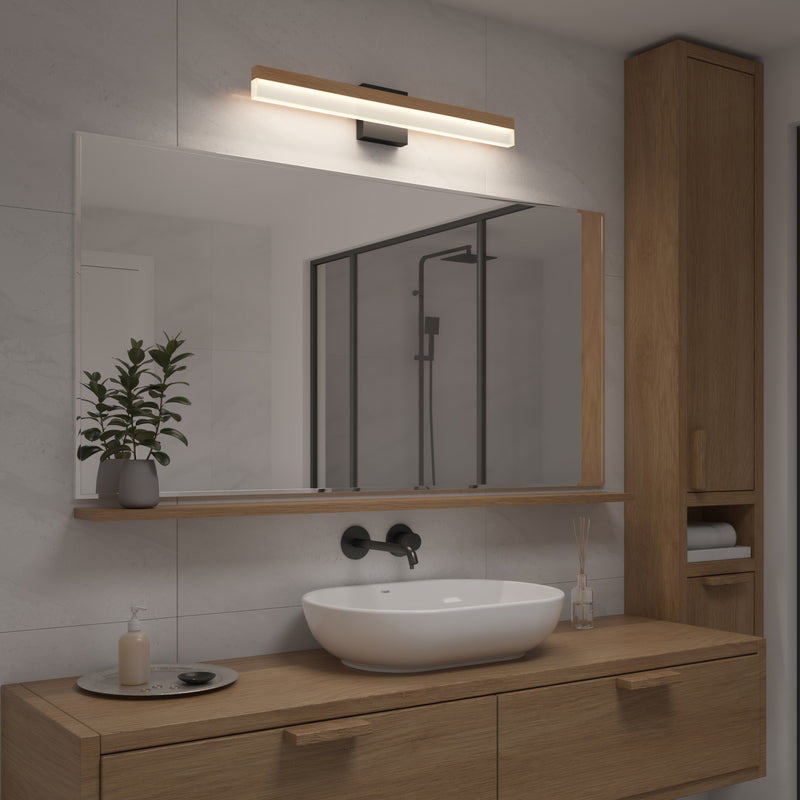 Modern bathroom with a large mirror, wooden vanity, oval sink, and wall-mounted faucet. The Artika Neil 27-in Integrated LED Vanity Light Bar provides ideal lighting. Glass shower with black frame is reflected alongside potted plant and decor.