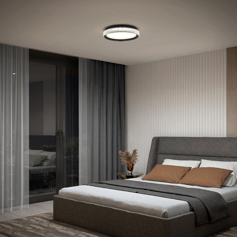 Modern bedroom with a grey upholstered bed, brown and white bedding, gray throw blanket, nightstand with a vase of dried plants, sheer and dark curtains, and the Artika Aston 15 in. LED modern flush mount light (5 CCT) on the ceiling.