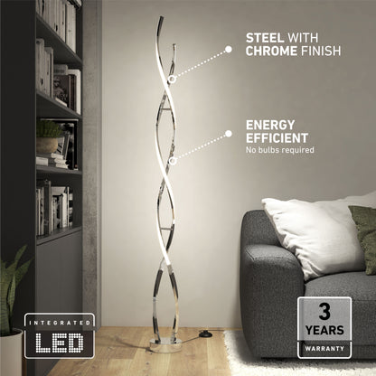 The Swirl modern LED floor lamp by Artika features a sleek chrome-finished steel design. Placed next to a gray sofa and bookshelf, it offers energy efficiency, integrated LED lighting, and comes with a 3-year warranty.