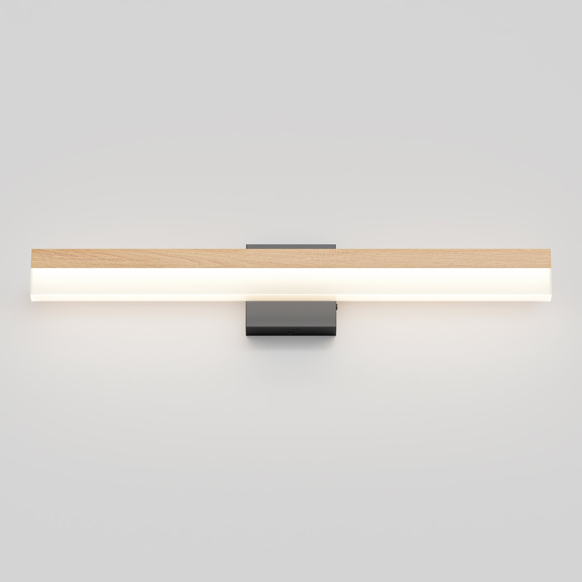 Minimalist wall-mounted light fixture with a long horizontal bar featuring a wood-like top and a glowing white underside, attached to a rectangular black base against a plain light gray wall.